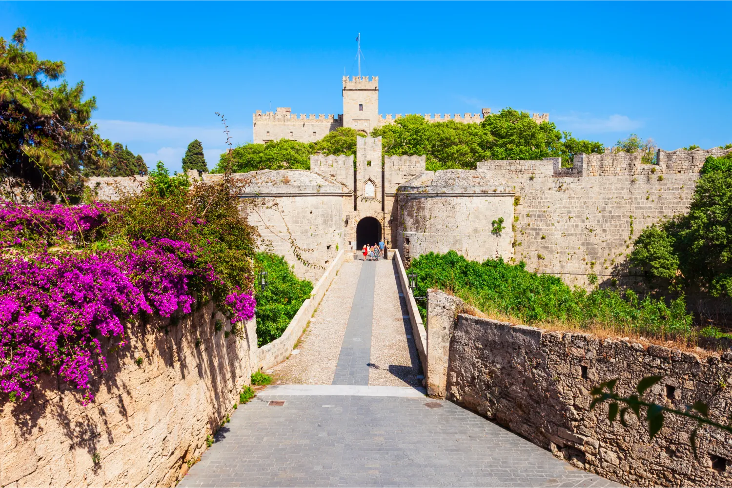 Chemin menant au château dominant de Rhodes, entouré de fleurs et d'une végétation luxuriante