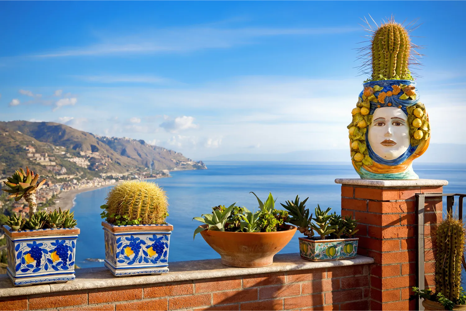 Pots de fleurs sur un balcon en Sicile et belle vue de la côte de Taormina en arrière-plan